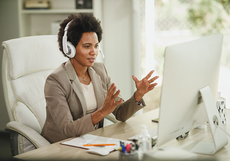 Shot of an attractive African businesswoman with headphones having video call while working on computer during corona virus pandemic.